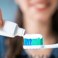Woman squeezing toothpaste onto a toothbrush.
